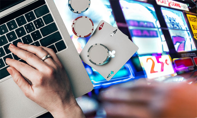Mains sur l'ordinateur portable par des cartes et des jetons sur une table de casino